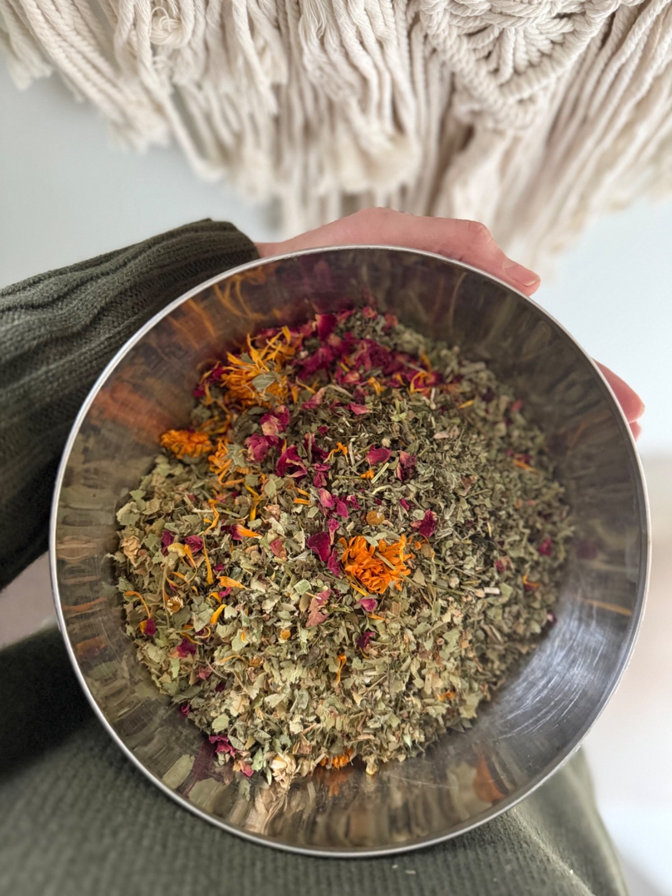 Mixing a loose-leaf herbal blend in a metal bowl