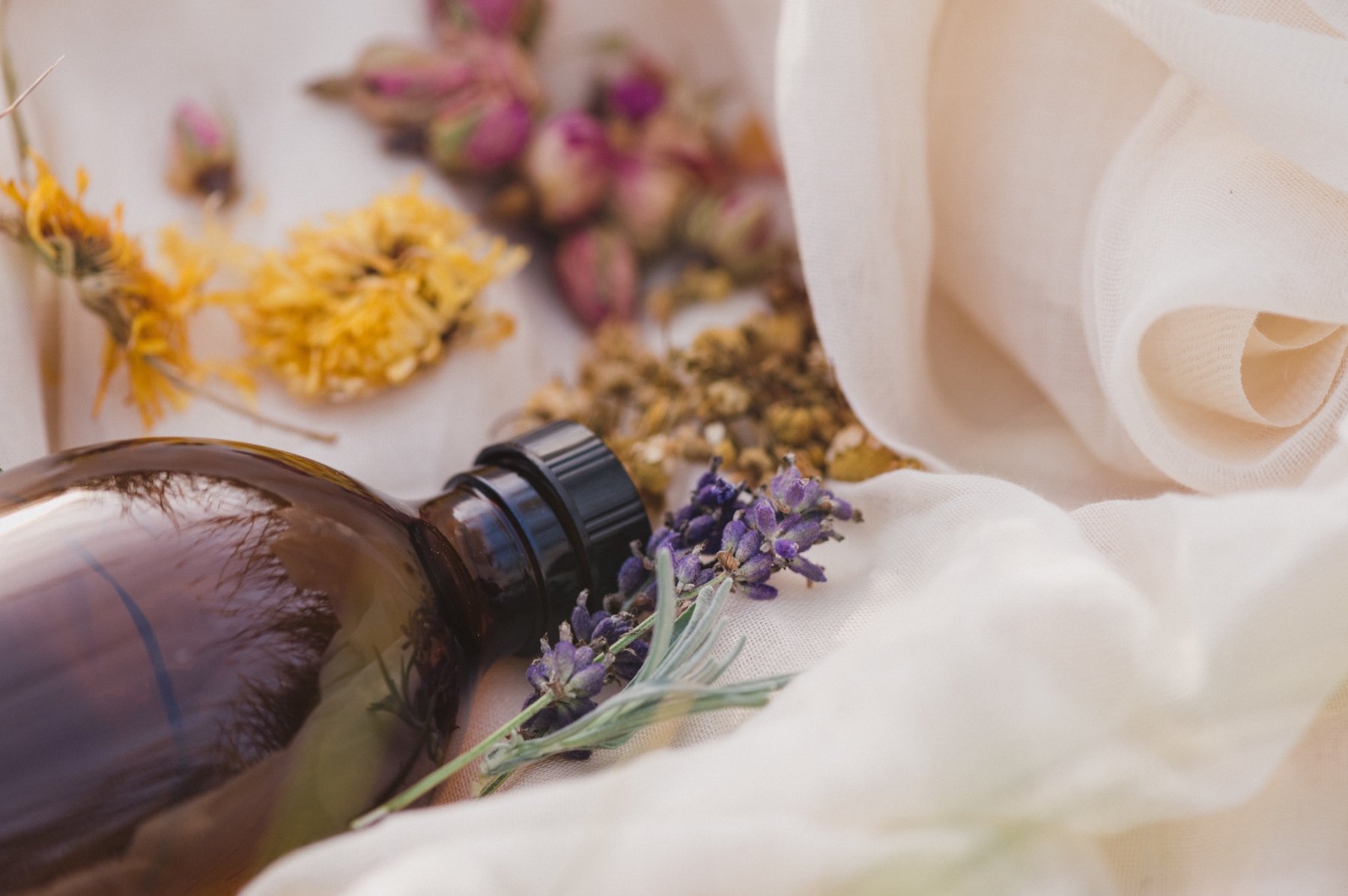 An amber herbal bottle surrounded by dried flowers